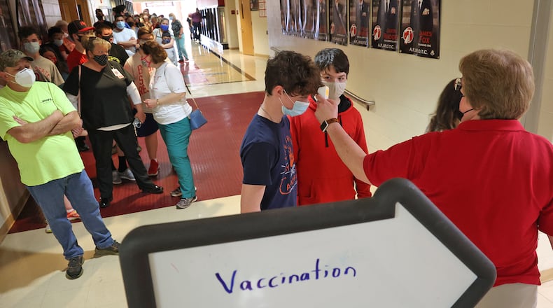 Suzanne Massie, takes temperatures before people enter the COVID vaccination clinic at Tecumseh High School Wednesday. BILL LACKEY/STAFF