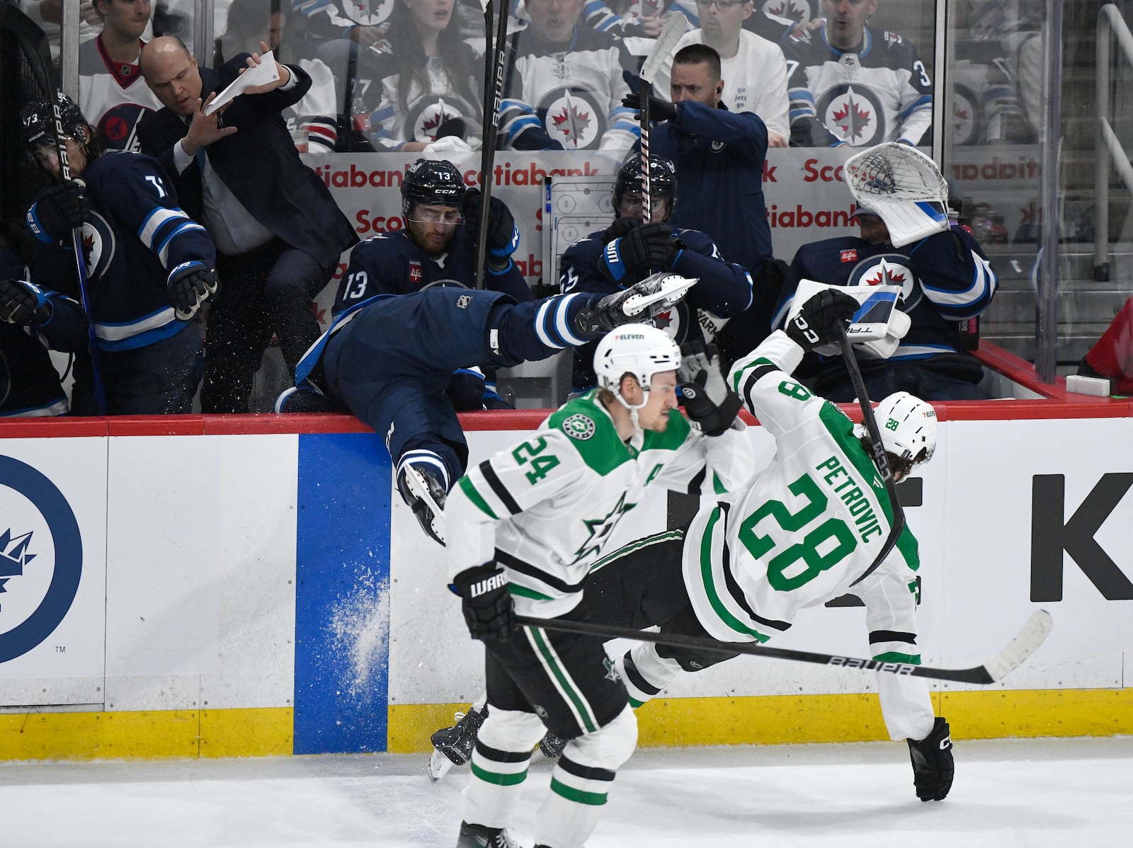 Dallas Stars' Alexander Petrovic (28) checks Winnipeg Jets' Adam Lowry, center, into the bench during the second period of Game 2 of a second-round NHL hockey playoff series in Winnipeg, Manitoba, Friday, May 9, 2025. (Fred Greenslade/The Canadian Press via AP)