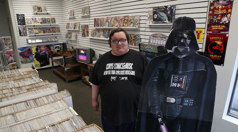Cory Knisley, the owner of Cory’s Comics & Music, with a friend in the shop Monday. BILL LACKEY/STAFF