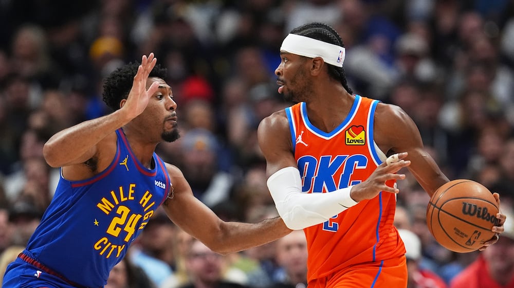 Oklahoma City Thunder guard Shai Gilgeous-Alexander, right, looks to pass the ball as Denver Nuggets guard Jalen Pickett defends in the first half of an NBA basketball game Sunday, Feb. 1, 2026, in Denver. (AP Photo/David Zalubowski)