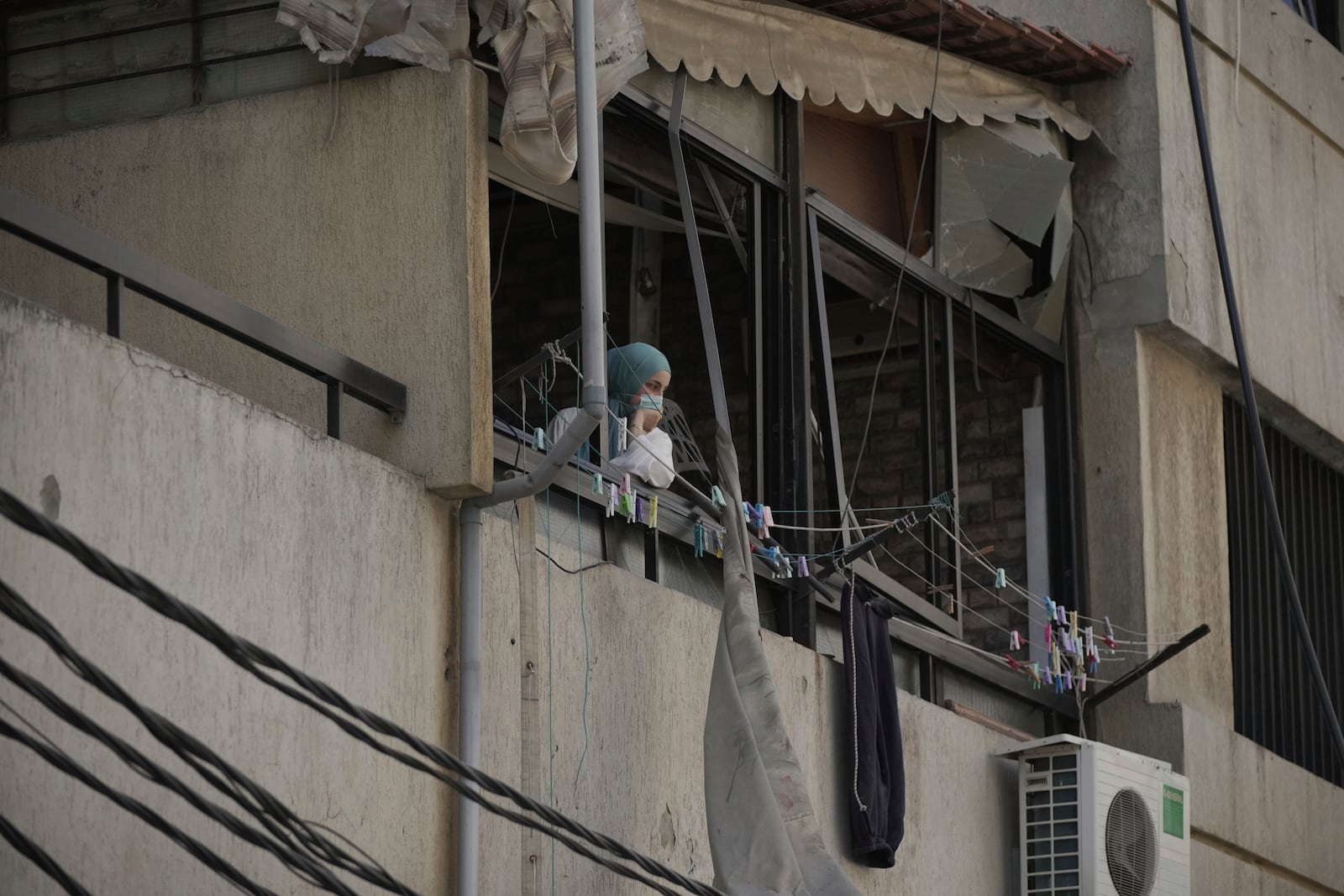 A citizen inspects the destruction from her apartment balcony after Israeli army strikes in the Dahiyeh suburb of Beirut, Lebanon, Friday, June 6, 2025. (AP Photo/Hassan Ammar)