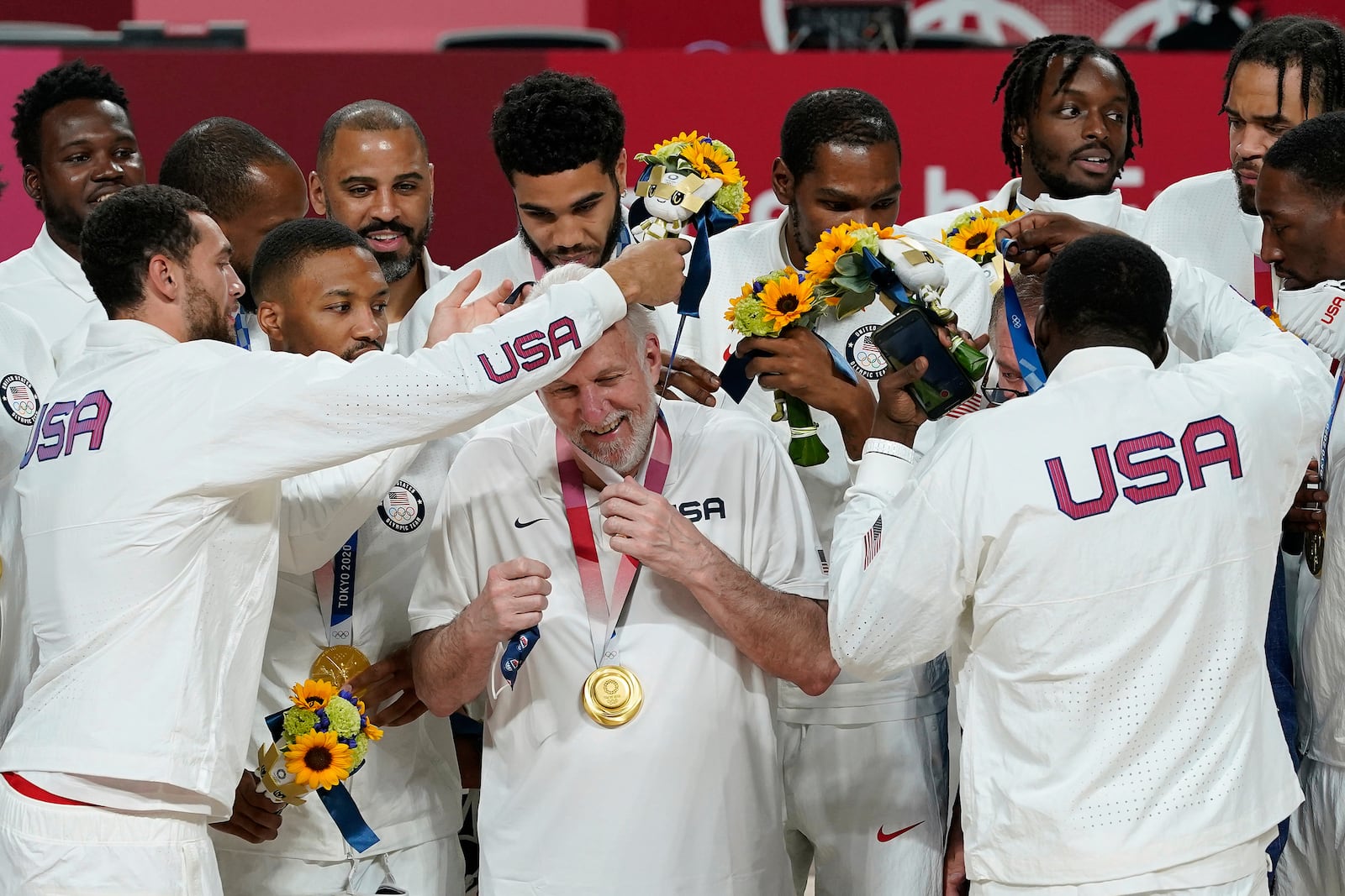 FILE - United States players put a gold medal on head coach Gregg Popovich during the men's basketball medal ceremony at the 2020 Summer Olympics, Saturday, Aug. 7, 2021, in Tokyo, Japan. (AP Photo/Charlie Neibergall, File)