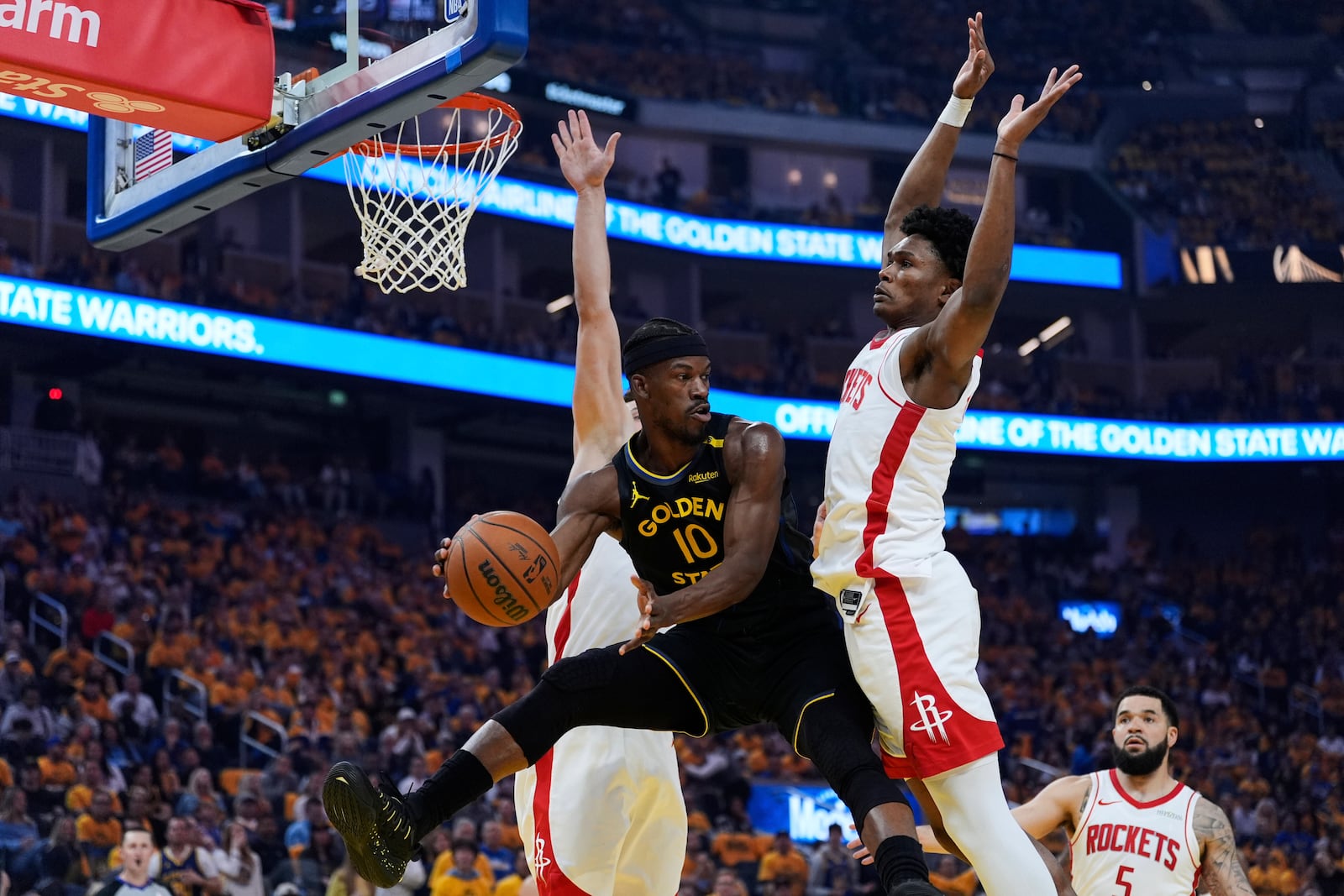 Golden State Warriors forward Jimmy Butler III (10) passes the ball between Houston Rockets center Alperen Sengun, left, and forward Amen Thompson during the first half of Game 6 of an NBA basketball first-round playoff series Friday, May 2, 2025, in San Francisco. (AP Photo/Godofredo A. Vásquez)