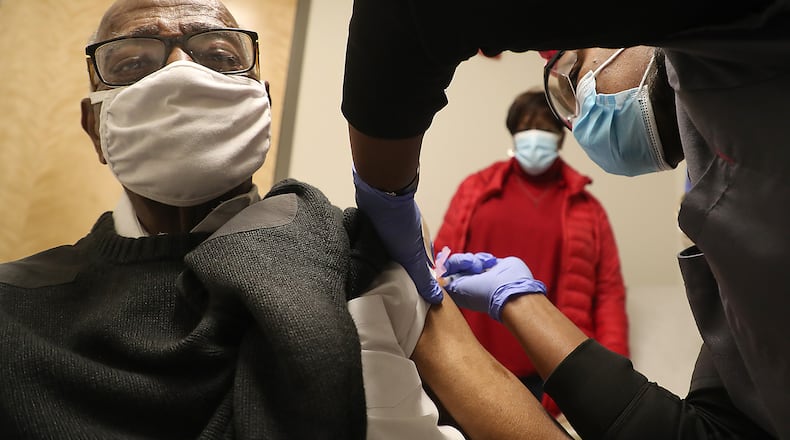 Former Springfield Police Chief Roger Evans gets a COVID-19 vaccine injection from Sherita Bloxom, a nurse at the Rocking Horse Center Thursday as his wife, Sharon, waits in the background. The Rocking Horse Center started giving out the vaccine to seniors over 80 Thursday. BILL LACKEY/STAFF
