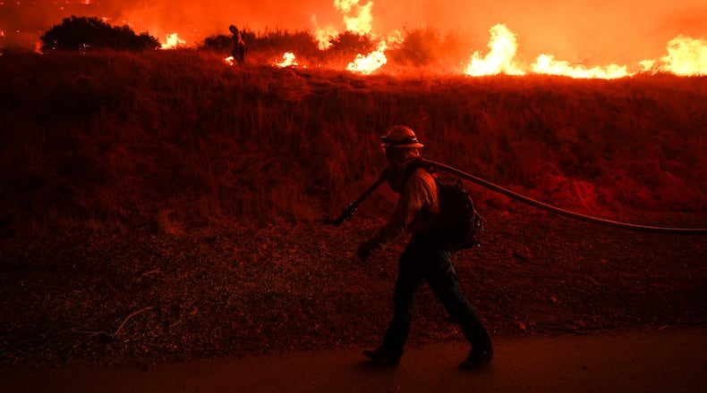 FILE - A firefighter monitors flames caused by the Hughes Fire along Castaic Lake in Castaic, Calif., Jan. 22, 2025. (AP Photo/Jae C. Hong, File)