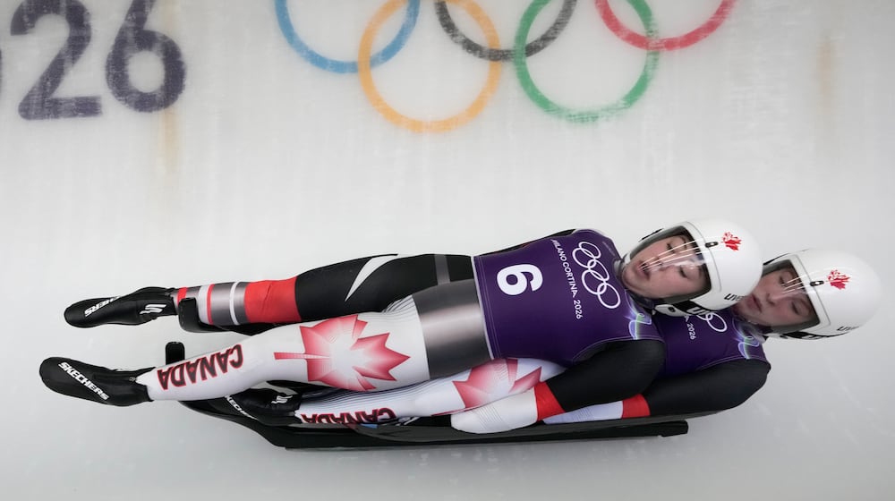 Canada's Beattie Podulsky, left, and Kailey Allan, right, slide down the track during a women's doubles luge training session at the 2026 Winter Olympics, in Cortina d'Ampezzo, Italy, Sunday, Feb. 8, 2026. (AP Photo/Aijaz Rahi)