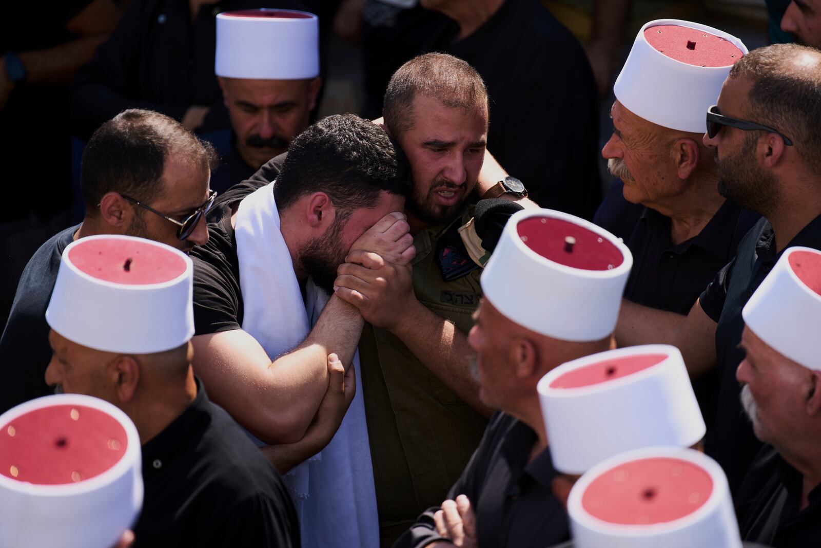 Relatives of Druze Israeli captain Amir Saad, who was killed in a battle in the Gaza Strip, mourn during his funeral in the village of Yanuh Jat, northern Israel, Sunday, July 27, 2025. (AP Photo/Ariel Schalit)