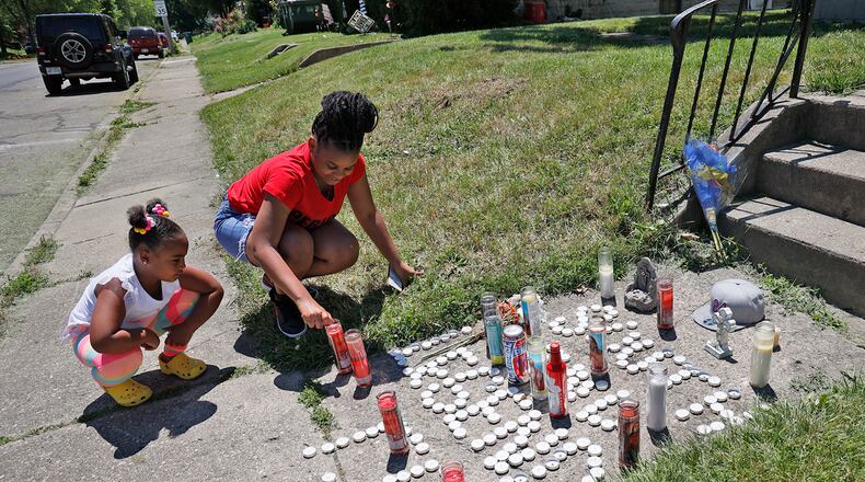 Corah Belle, right, and Chandlor Robinson, cousins of Eric Cole, light some of the candles that had gone out on the memorial along South Center Street near where Cole was shot and than run over by a responding police officer Sunday night. BILL LACKEY/STAFF