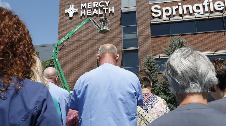 Employees at Springfield Regional Medical Center bow their heads as a prayer is read after the new Mercy Health sign is unveiled on the front of hospital. Bill Lackey/Staff