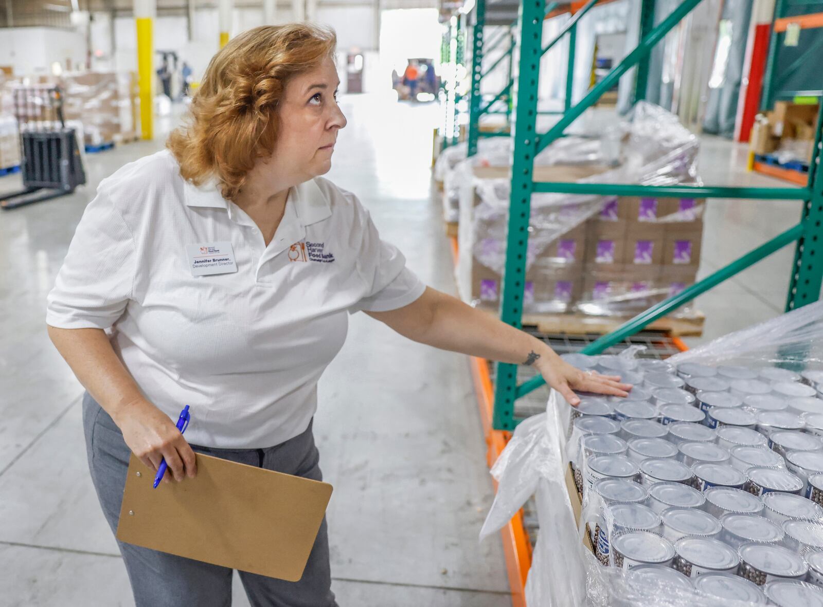 Jennifer Brunner, development director of Second Harvest Food Bank, looks at canned goods in the warehouse of Second Harvest Food Bank on Wednesday, July 9, 2025, in Springfield. JOSEPH COOKE/STAFF
