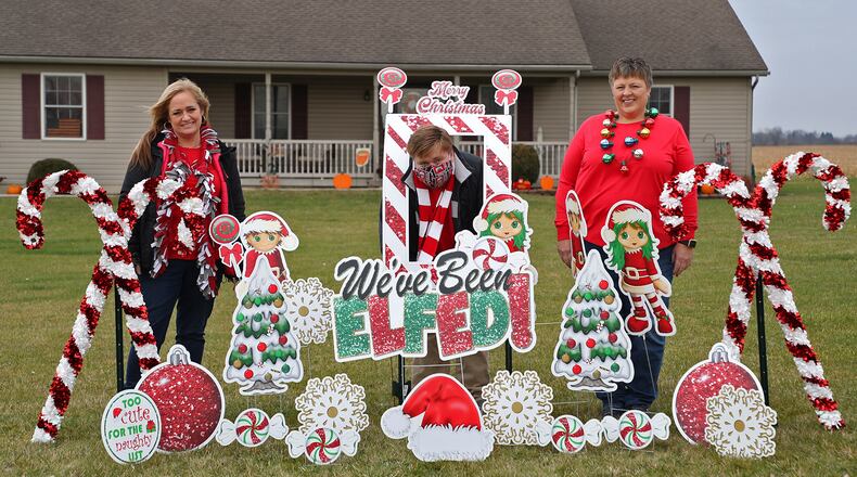 Robyn Fell, left, and her son, Zan, with Kim Harris in a front yard that has been "Elfed" Tuesday. BILL LACKEY/STAFF