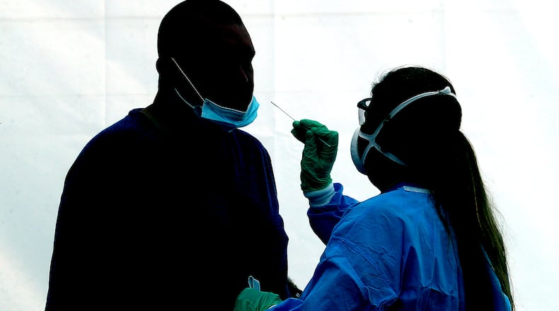 A man is silhoutted against the wall of a white tent as he gets a COVID-19 test at the Clark County Combined Health District's free COVID testing clinic at Hayward Middle School. BILL LACKEY/STAFF