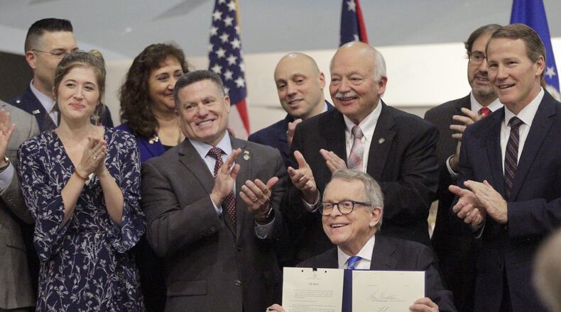 Gov. Mike DeWine signed Ohio Senate Bill 7 Monday during a ceremony at the National Museum of the U.S. Air Force. The bill mandates state occupational licensing agencies issue temporary licenses and certificates to members of the military and spouses who are licensed in another jurisdiction and have moved to Ohio for military duty. From left to right are Brianna McKinnon, a military spouse and special education teacher, Rep. Rick Perales, Sen. Bob Hackett and Lt. Gov. Jon Husted. LISA POWELL / STAFF