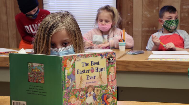 A first grade student reads a book after finishing her classwork at The Village. BILL LACKEY/STAFF