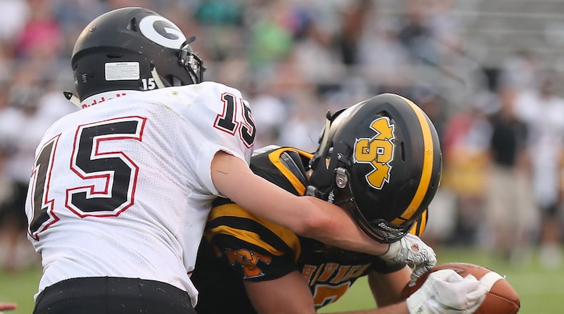 Shawnee’s Pete Mueller holds onto a touchdown pass even with Greenon’s Clay Hough’s arm in his facemask during last Friday’s season opener. BILL LACKEY/STAFF