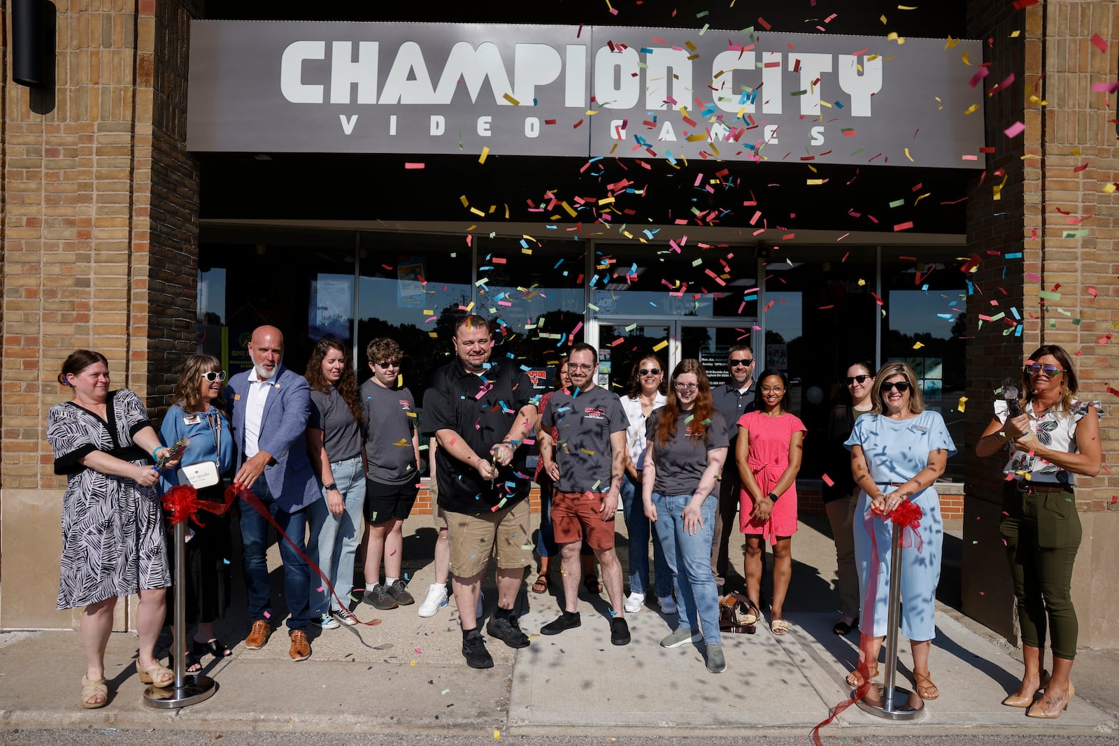 Owner Kenneth Seelig III, left center, watches confetti fly around him after cutting the ribbon during a grand opening for the expansion of Champion City Games and Hobby on Friday, July 11, 2025, in Springfield. JOSEPH COOKE/STAFF