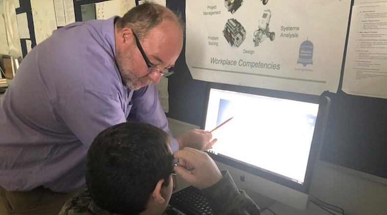 Springfield High School teacher Chuck Stumpf, who worked as an engineer before becoming a teacher, helps a student understand rapid prototyping which is common in engineering and manufacturing fields.