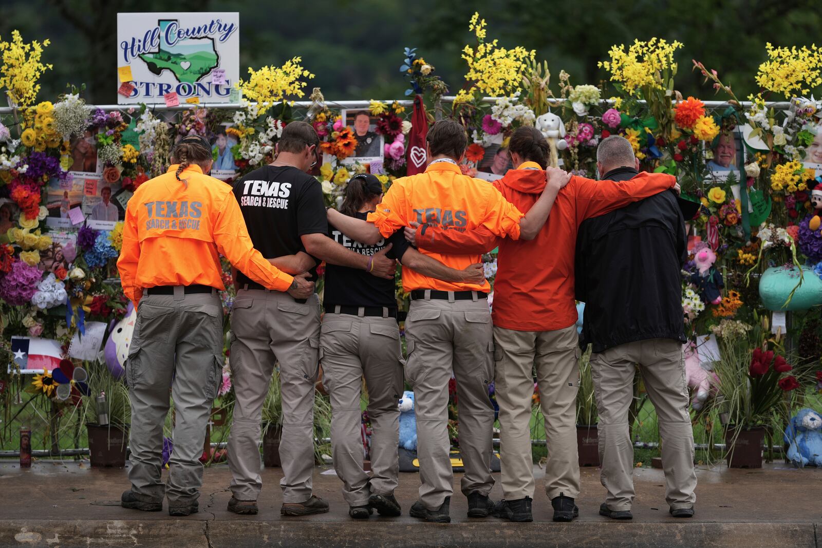 Members of a search and rescue team embrace as they visit a memorial wall for flood victims, Sunday, July 13, 2025, in Kerrville, Texas. (AP Photo/Eric Gay)
