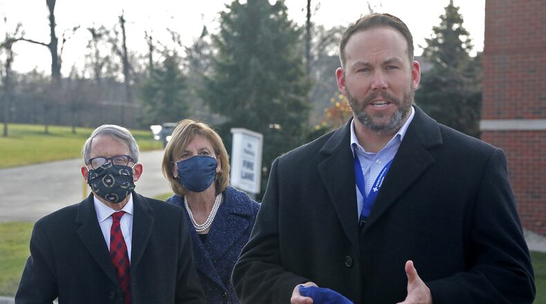 Springfield Regional Medical Center President Adam Groshans speaks to members of the press as Gov. Mike DeWine and his wife, Fran, listen on Dec. 15. Groshans said guessing when those in group 1b of the state's vaccination distribution plan is like "looking into a crystal ball." BILL LACKEY/STAFF