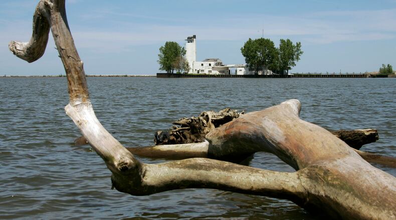 FILE - A dead tree on the Lake Erie shoreline frames the old Coast Guard lifeboat station at the mouth of the Cuyahoga River in Cleveland, May 29, 2008. Tuesday, Oct. 18, 2022, is the 50th anniversary of Congress passing the Clean Water Act to protect U.S. waterways from abuses like the oily industrial pollution that caused Ohio's Cuyahoga River to catch on fire in 1969. (AP Photo/Mark Duncan, File)