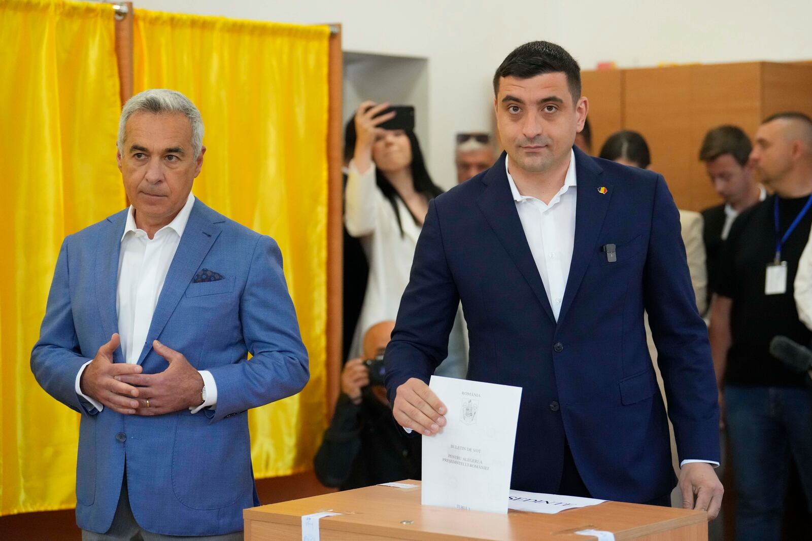Presidential candidate George Simion, right, casts his vote next to Calin Georgescu, winner of the first round of last year's annulled election, during the first round of the presidential election redo in Bucharest, Romania, Sunday, May 4, 2025. (AP Photo/Vadim Ghirda)