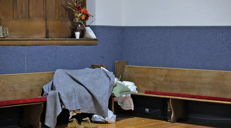 A homeless person sleeps on a bench at the Springfield Warming Center Wednesday, Jan. 9, 2025. BILL LACKEY/STAFF
