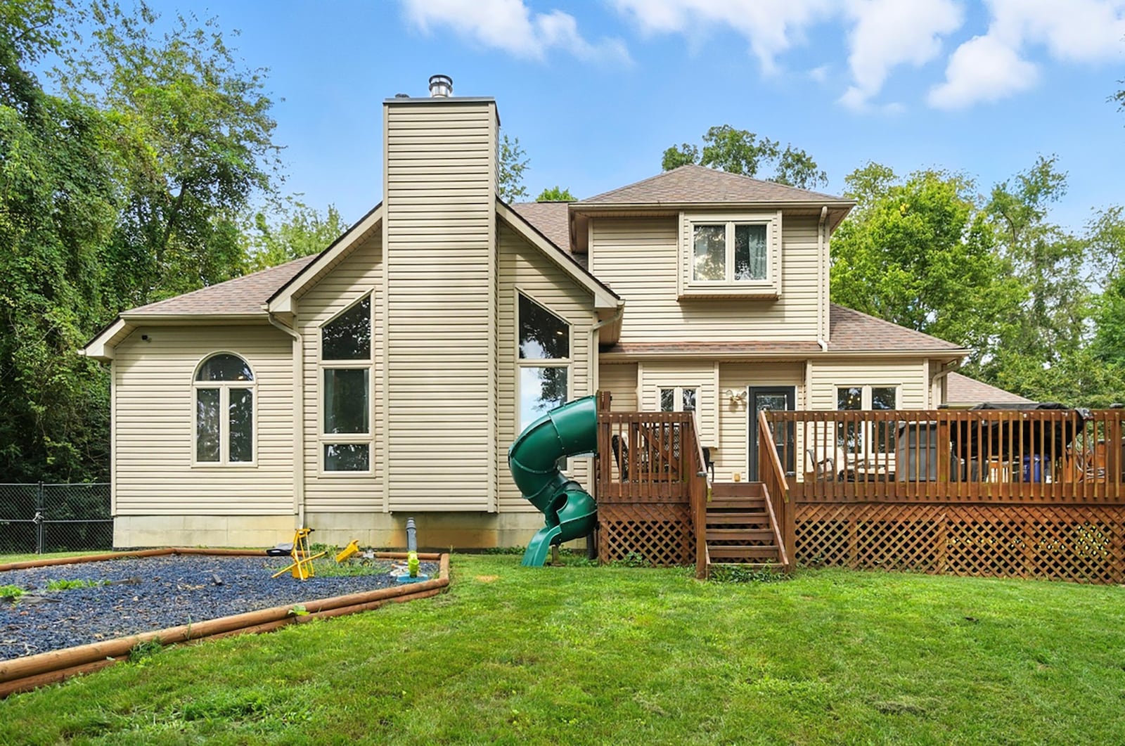 The back of the home features a wood deck with railings and a mulched play area with landscaping timbers. CONTRIBUTED