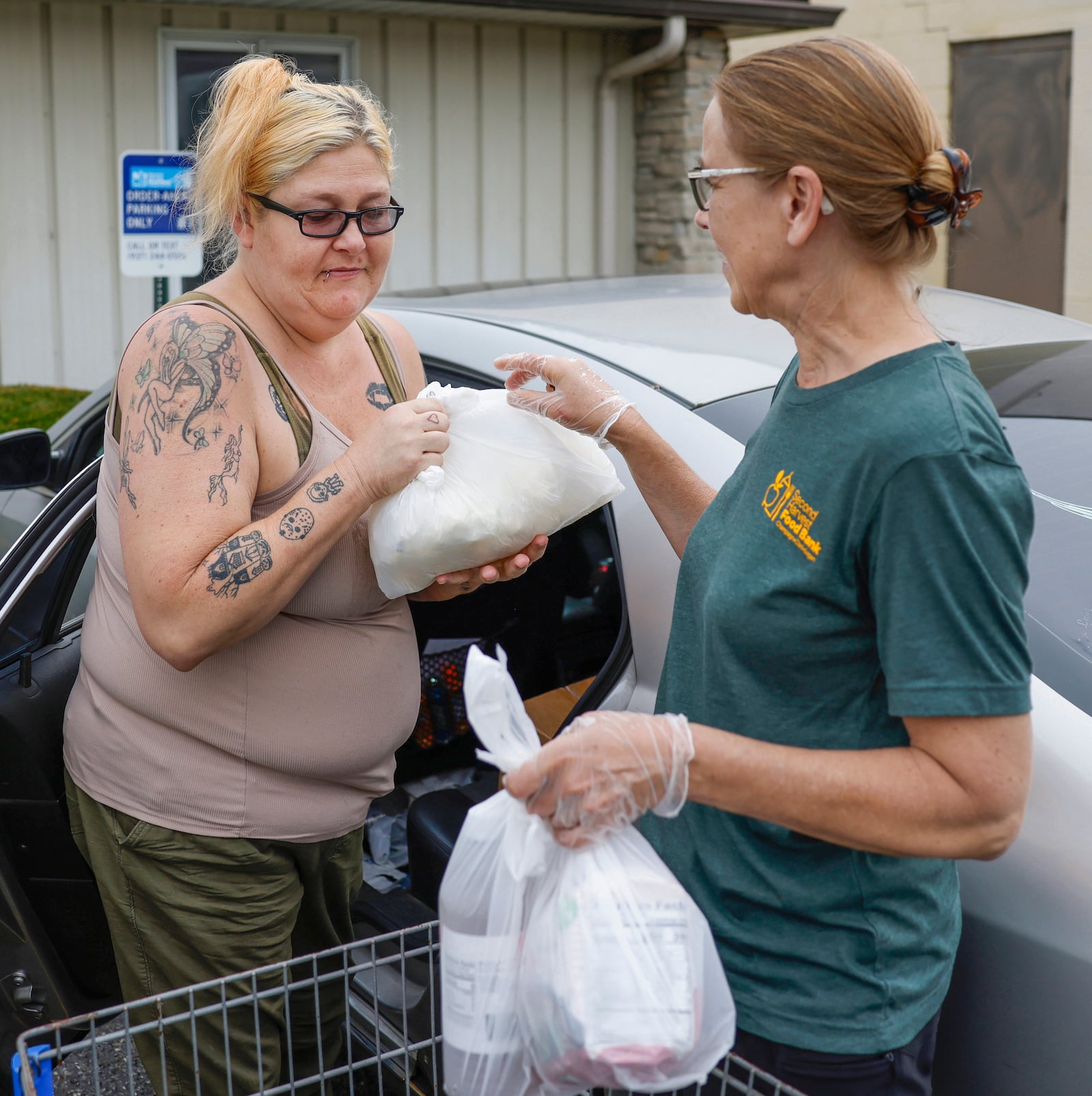 Holly Holland, left, of Springfield, receives groceries from volunteer Carol Conrad as part of OrderAhead, Second Harvest Food Bank's choice program, on Wednesday, July 9, 2025, at Second Harvest Food Bank. JOSEPH COOKE/STAFF