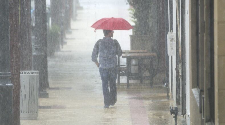 A pedestrian tries to keep dry on Clematis Street. (Lannis Waters / The Palm Beach Post)