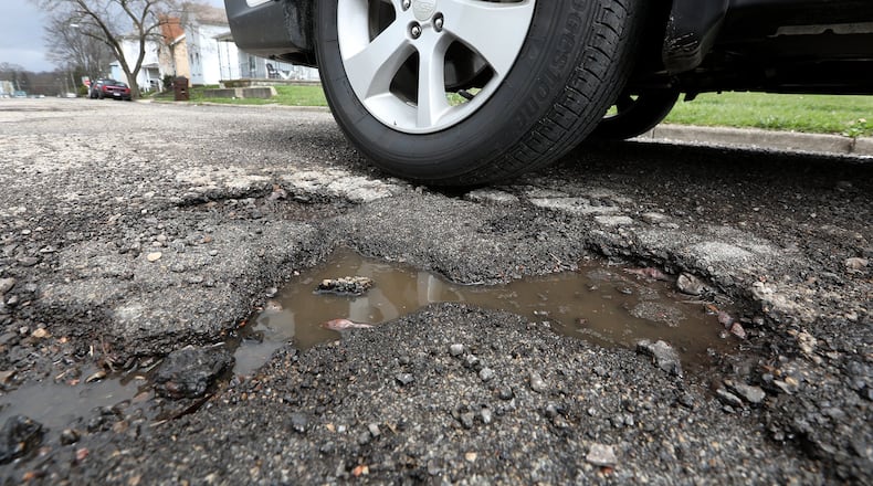 A car drives past a pothole along Race Street Monday, April 16, 2018. City of Springfield has announced plans to repave several city streets. It will use money from a levy passed in Springfield in 2017.