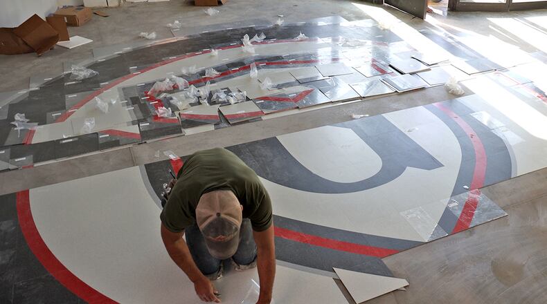 Greenon Local Schools will host final walkthroughs of Greenon High School and Indian Valley. Here, a worker installs a tile "G" in the hallway of the new Greenon School. BILL LACKEY/STAFF