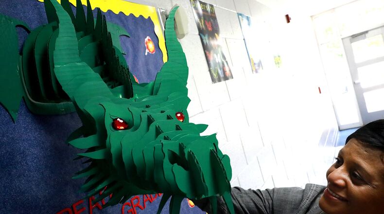 Deborah Howard, the principal at Fulton Elementary in Springfield, stops to admire one of the dragons that decorate the halls of the school Thursday in preparation of the new school year. BILL LACKEY/STAFF