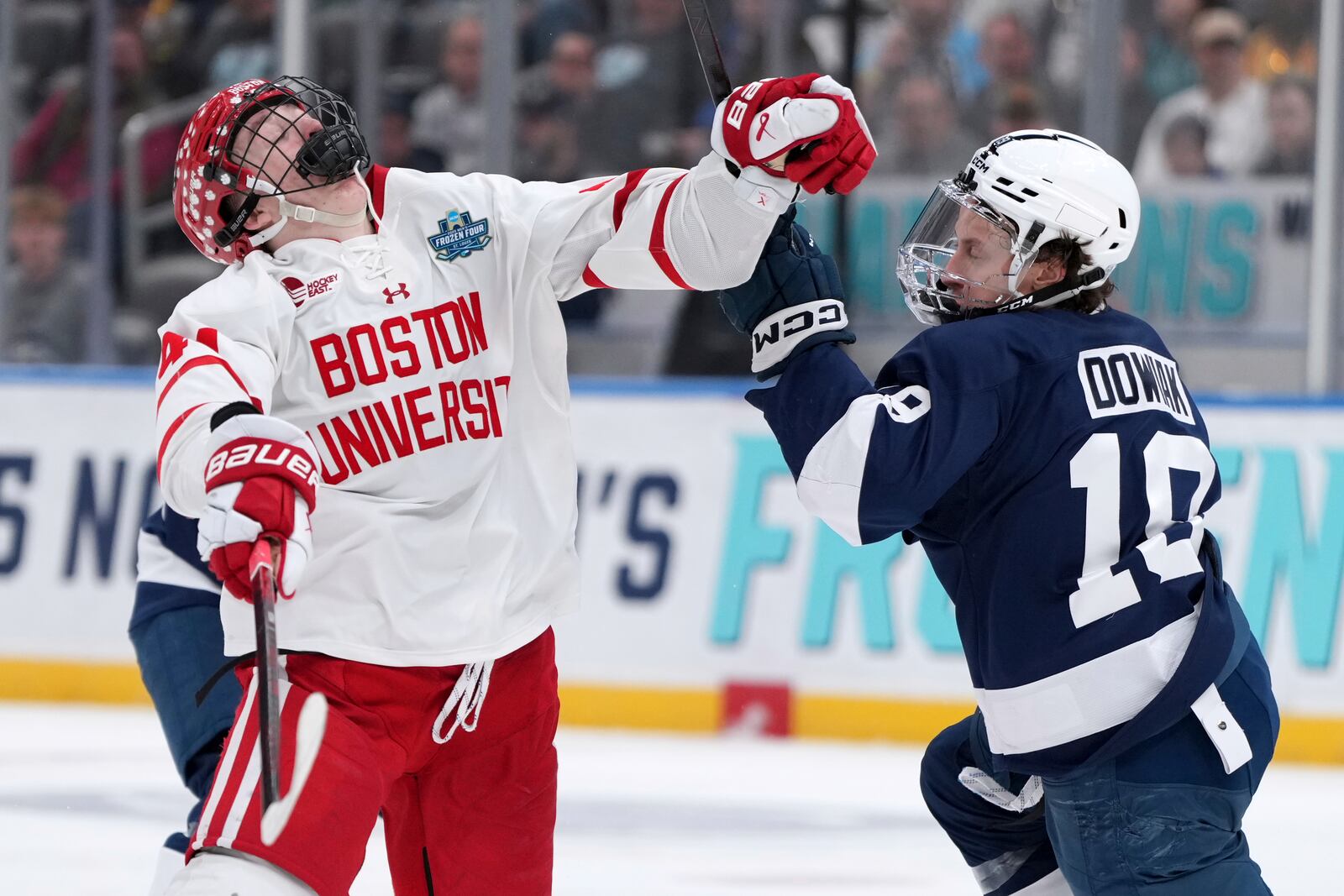 Boston University's Cole Hutson, left, recoils after being hit by Penn State's Dane Dowiak (19) during the third period in a semifinal game in the NCAA Frozen Four men's college hockey tournament, Thursday, April 10, 2025, in St. Louis (AP Photo/Jeff Roberson)