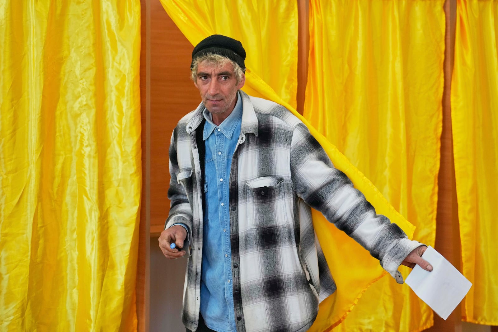 A man exits a voting cabin before casting his vote in the first round of the presidential election redo in Mogosoaia, Romania, Sunday, May 4, 2025. (AP Photo/Vadim Ghirda)
