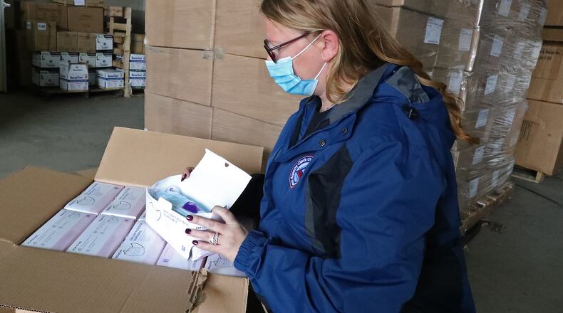 Michelle Clements-Pitstick, director of the Clark County EMA, opens up one of the cases filled with thousands of masks that they will distribute in the county to try and slow down the rise in COVID-19 cases in the county. BILL LACKEY/STAFF