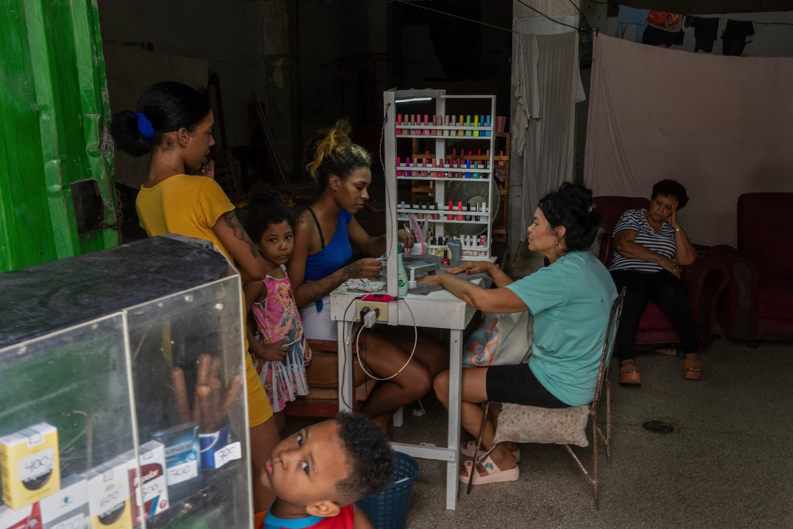 A manicurist works on a client's nails as others wait at a home-run nail salon in Havana, Cuba, Monday, July 7, 2025. (AP Photo/Ramon Espinosa)