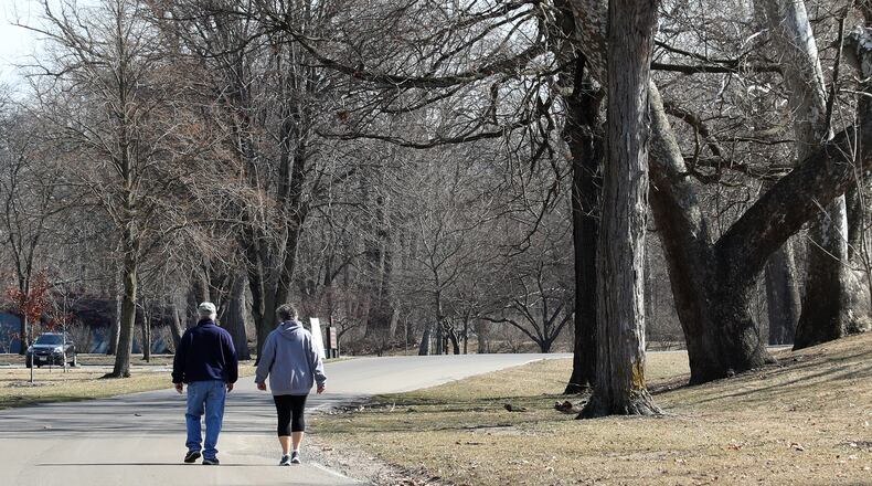 A couple enjoys the warm sunshine as they walks along the roadway in Snyder Park. BILL LACKEY/STAFF