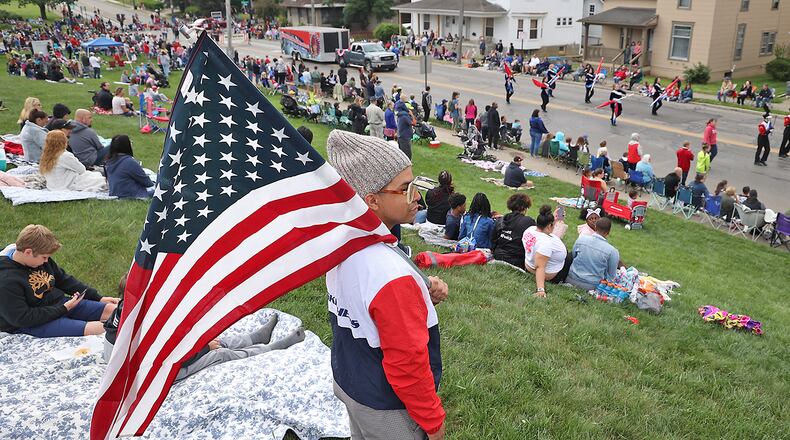 Kris Bruce, visiting from California, stands with a flag as he watches the annual Memorial Day Parade pass along McCreight Avenue in Springfield. Hundreds of people line the parade route to watch the parade, which was canceled last year do to COVID. BILL LACKEY/STAFF