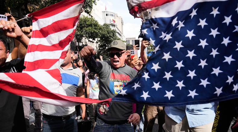 Government supporters rip an American flag in half during a protest in Caracas, Venezuela, Saturday, Jan. 3, 2026, after U.S. President Donald Trump announced that U.S. forces had captured President Nicolás Maduro and first lady Cilia Flores. (AP Photo/Ariana Cubillos)