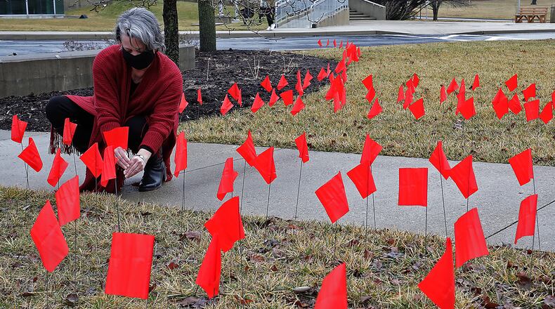 Lori Common, assitant to the vice president marketing diversity community impact at Clark State College, sets up one of the dozens of red flags on the lawn at the Springfield campus Tuesday. The goal of the Red Flag campaign is to keep safe and aware of domestic violence. BILL LACKEY/STAFF