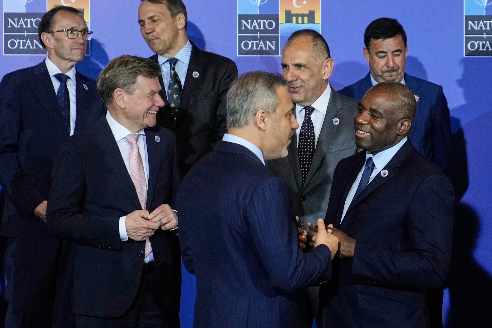 Turkey's Foreign Minister Hakan Fidan, center, talks to British Foreign Secretary David Lammy, right, next to Germany's Foreign Minister Johann Wadephul, left, as they wait for a group photo during a NATO's informal meeting of foreign ministers in Antalya, southern Turkey, Thursday, May 15, 2025. (AP Photo/Khalil Hamra)