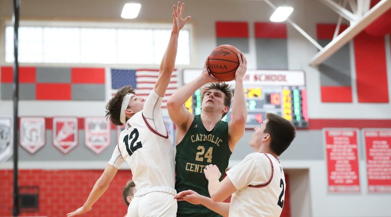 Catholic Central High School senior Tyler Galluch shoots the ball over Cedarville junior Tyler Cross (left) and senior Noah Burr (right) during their D-IV district semifinal game on Saturday night at Troy High School. CONTRIBUTED PHOTO BY MICHAEL COOPER