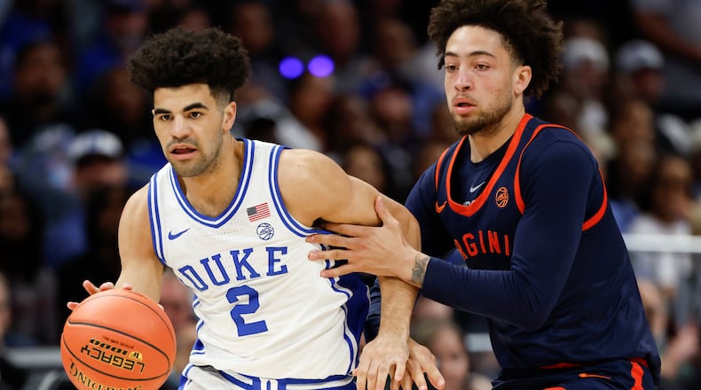 Duke guard Cayden Boozer (2) moves the ball against Virginia guard Sam Lewis during the first half of an NCAA college basketball game in the championship of the Atlantic Coast Conference tournament in Charlotte, N.C., Saturday, March 14, 2026. (AP Photo/Nell Redmond)
