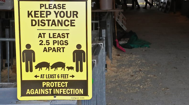Signs on all the barns warn people about social distancing at the Champaign County Fair Thursday. BILL LACKEY/STAFF