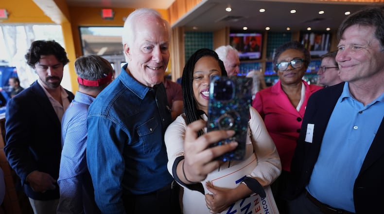 Sen. John Cornyn, R-Texas, left, poses for photos and visits with supporters during a campaign stop in Austin, Texas, Tuesday, Feb. 17, 2026. (AP Photo/Eric Gay)