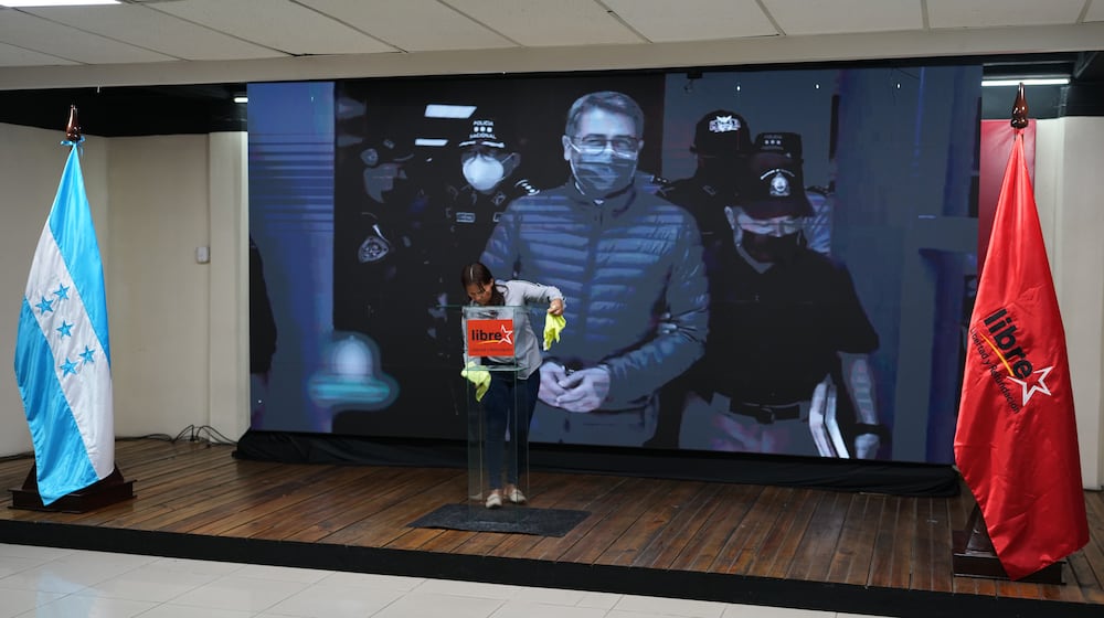 A screen displays an image of former Honduran President Juan Orlando Hernandez, a day after President Donald Trump said he plans to pardon Hernandez for a 2024 drug trafficking sentence, before the start of a press conference of Ruling party presidential candidate Rixi Moncada in Tegucigalpa, Honduras, Saturday, Nov. 29, 2025. (AP Photo/Moises Castillo)