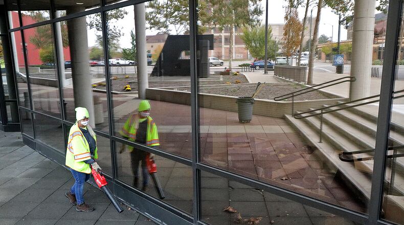 Joan Hawkins, a member of the City of Springfield Maintenance Department, blows the leaves off the City Hall Plaza Thursday. The city plans to make several improvements to the downtown plaza, which is reflected in the windows of City Hall. BILL LACKEY/STAFF