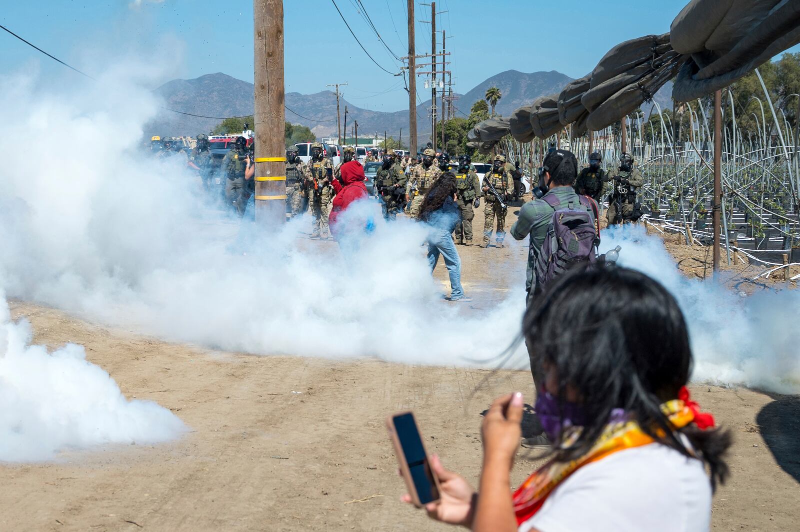 Federal immigration agents toss tear gas at protesters during a raid in the agriculture area of Camarillo, Calif., Thursday, July 10, 2025. (AP Photo/Michael Owen Baker)