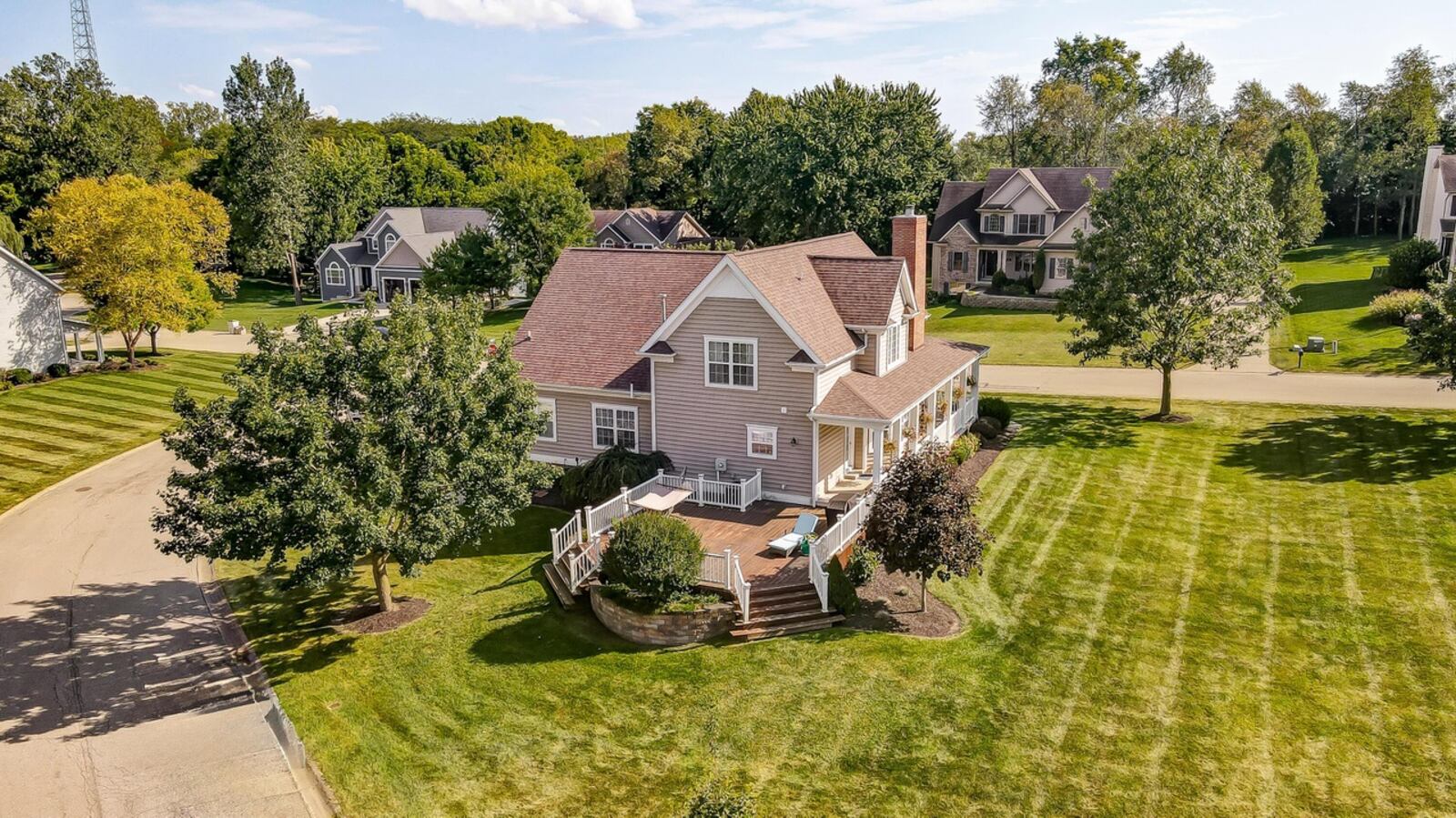 The home features a wraparound covered porch and a wood deck with railings. Contributed