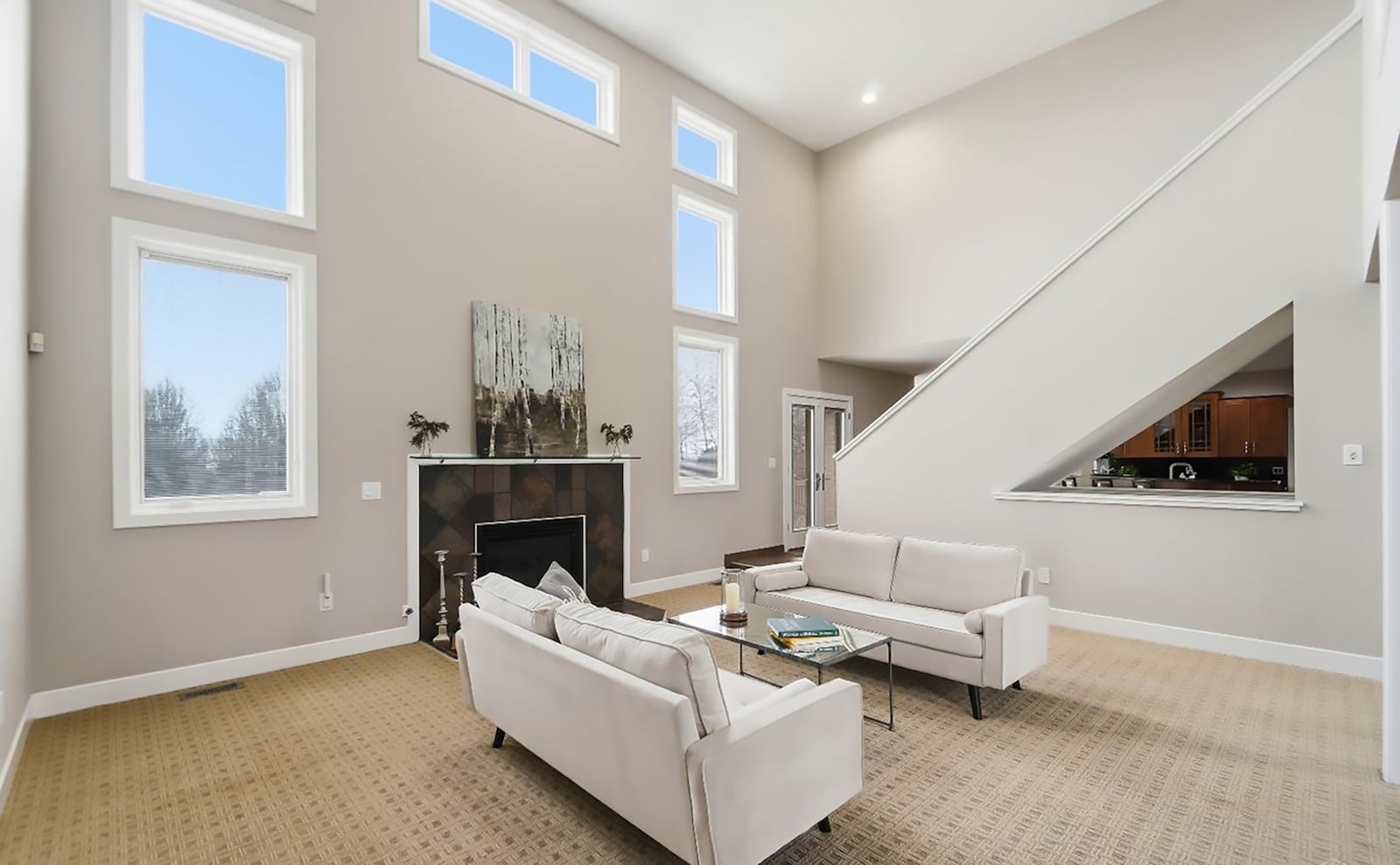 The two story living room has a gas fireplace, carpeting, recessed lighting and a ceiling fan. It is a step down from the kitchen. CONTRIBUTED